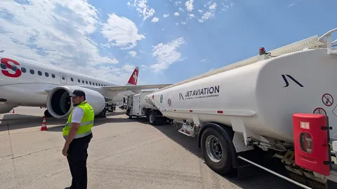 Un camion-citerne ravitaillant un avion de ligne sur le tarmac