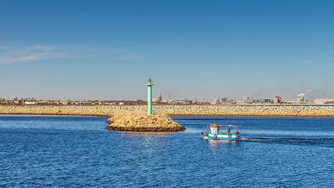 Le port de Gabès, dans le sud de la Tunisie, avec un bateau de pêche et la zone industrielle à l’horizon